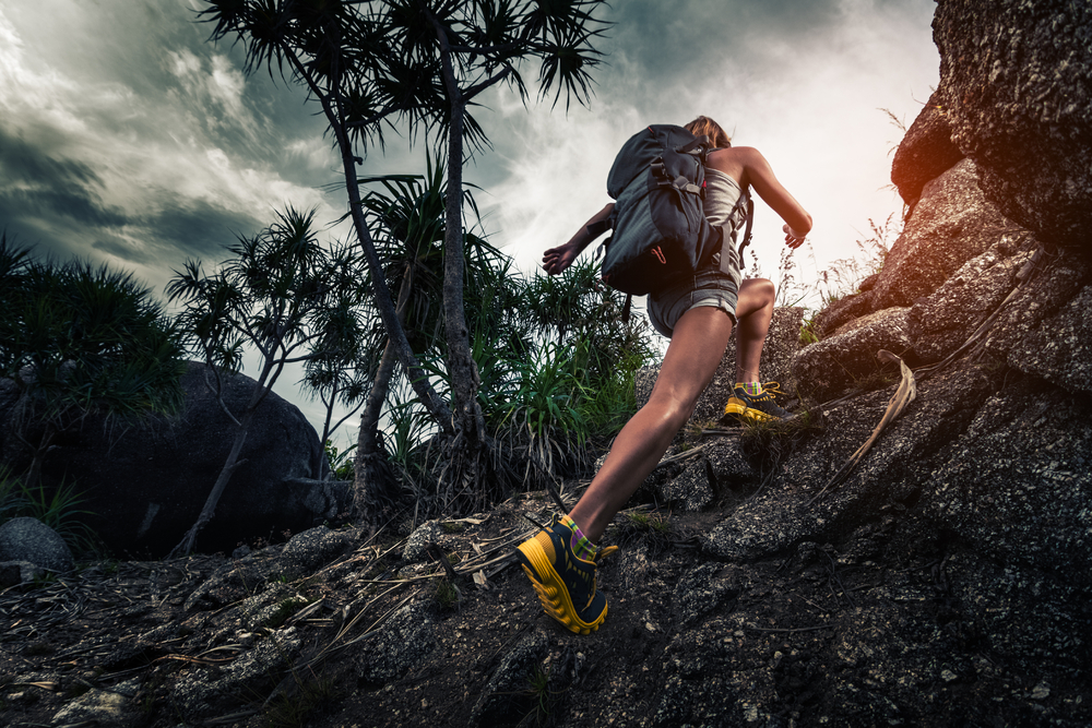 A woman hiker with a backpack climbs steep.