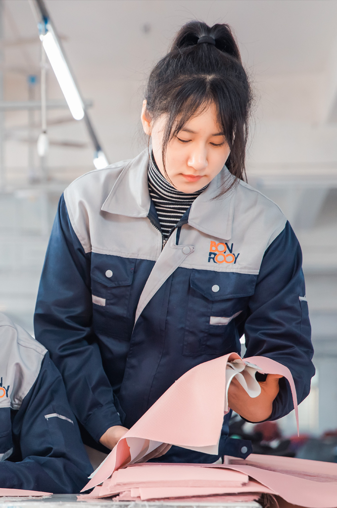 A worker meticulously checks the quality of fabric on the production line.