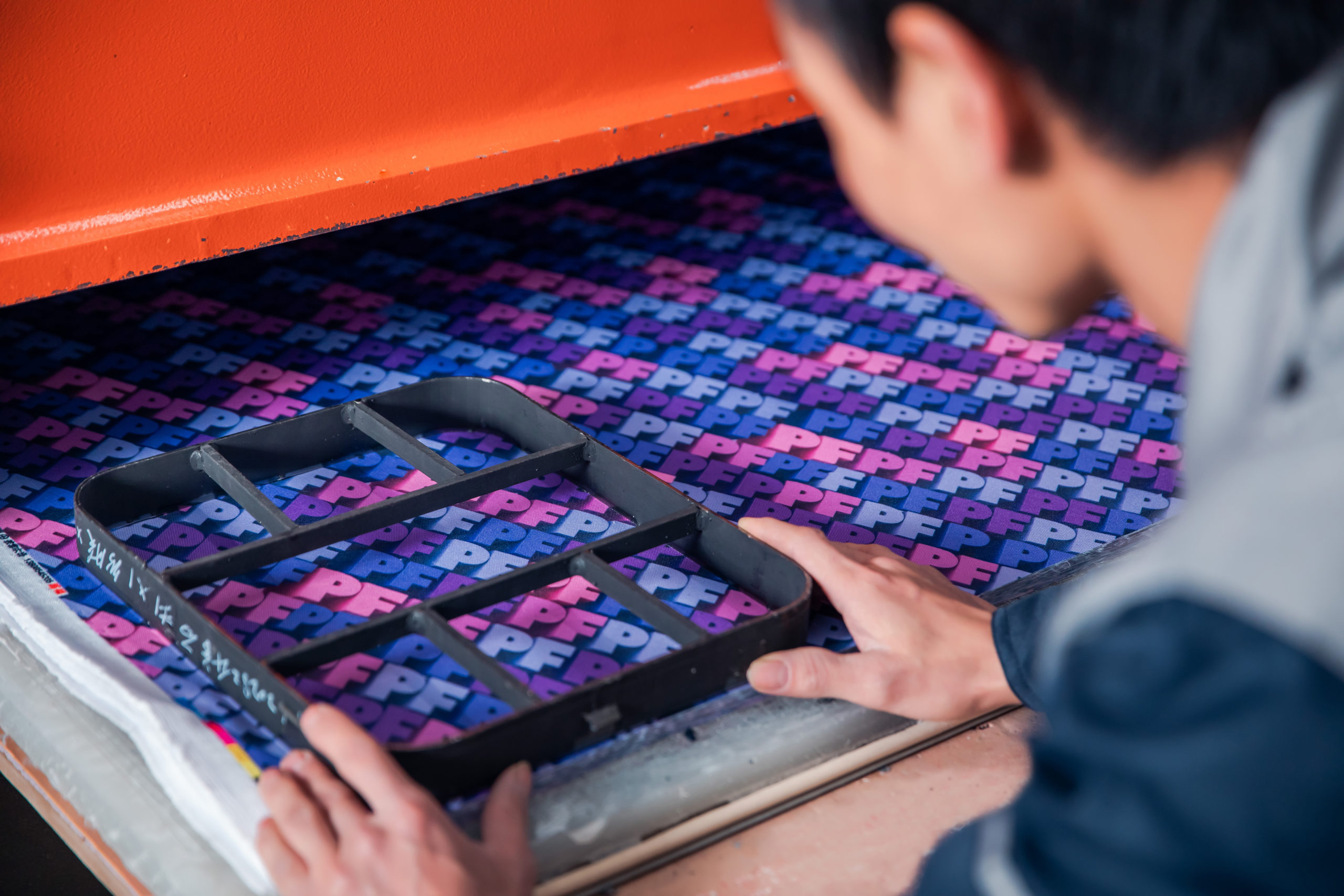 A worker carefully uses a cutting machine to cut fabric.